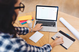 Modern work image young brunette woman in black glasses from back working with laptop on table. Creativity, graphic design, clever student, studying, freelancer